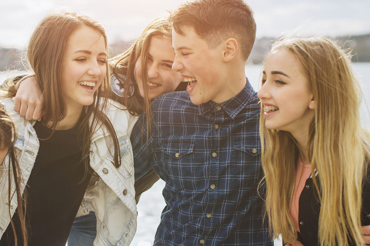 Fünf Jugendliche lachen zusammen am See