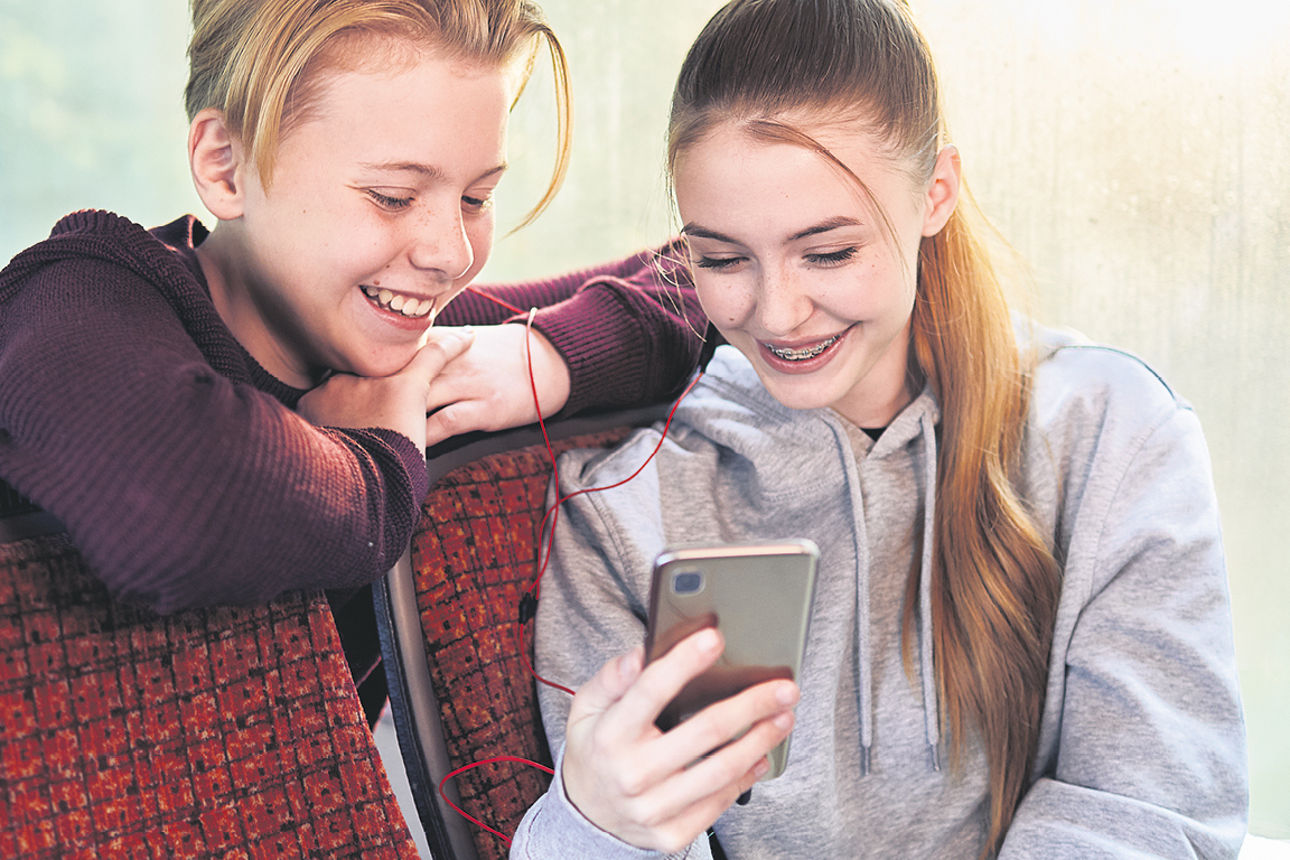 Zwei Jugendliche mit Handy im Bus