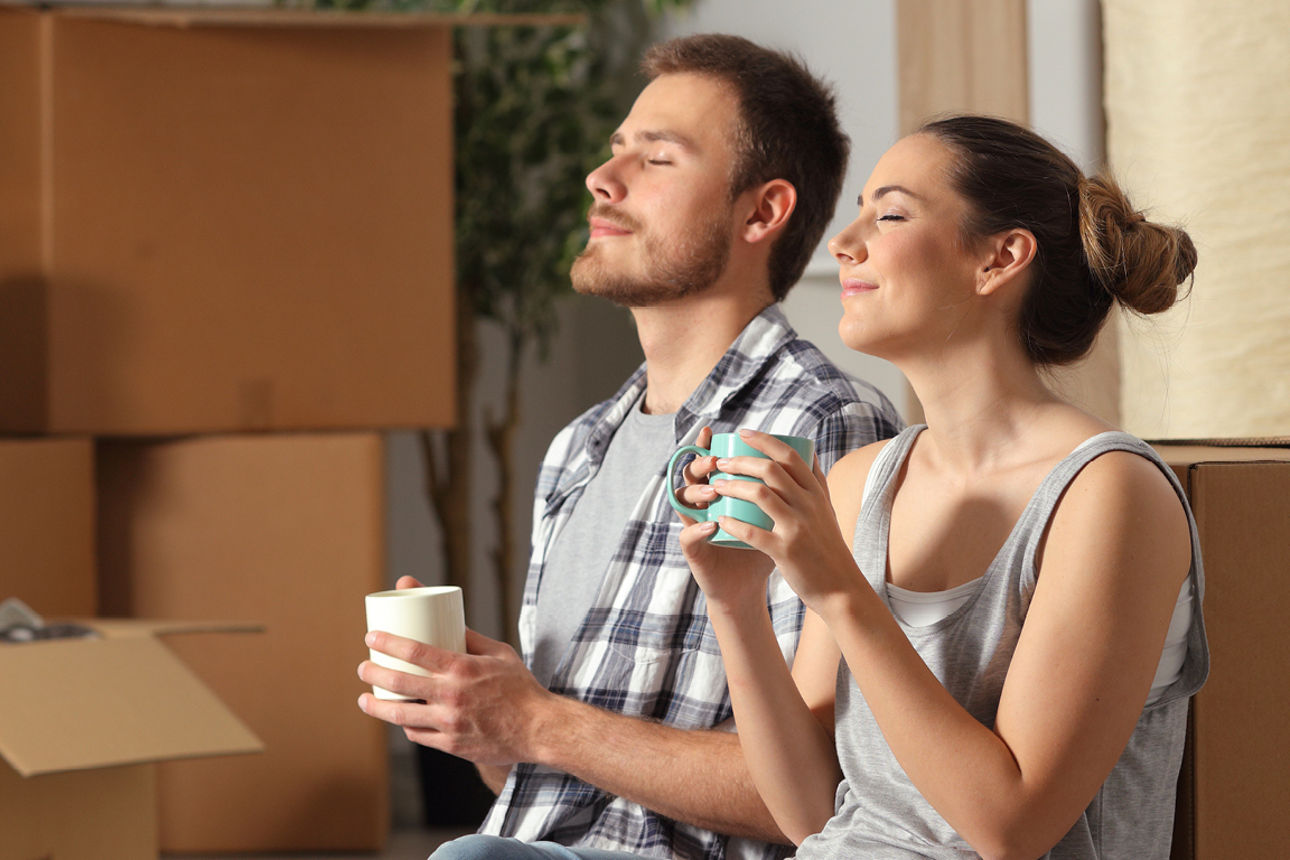 Frau und Mann mit Tasse zwischen Umzugskartons