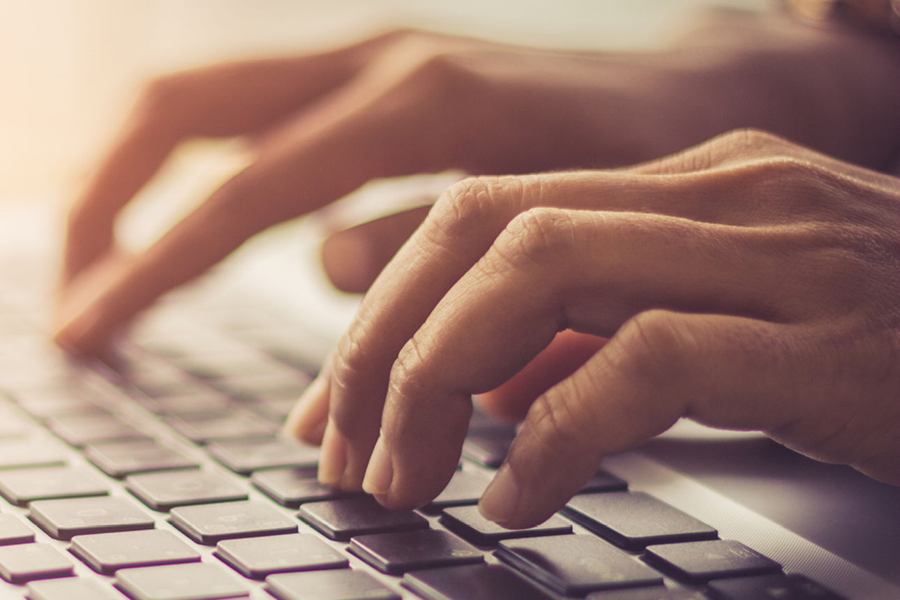 Eine Person hat die Hände auf der Tastatur und schreibt