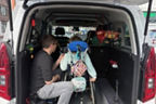 Vater bringt Kind im Rollstuhl über eine Rollstuhlrampe ins Auto