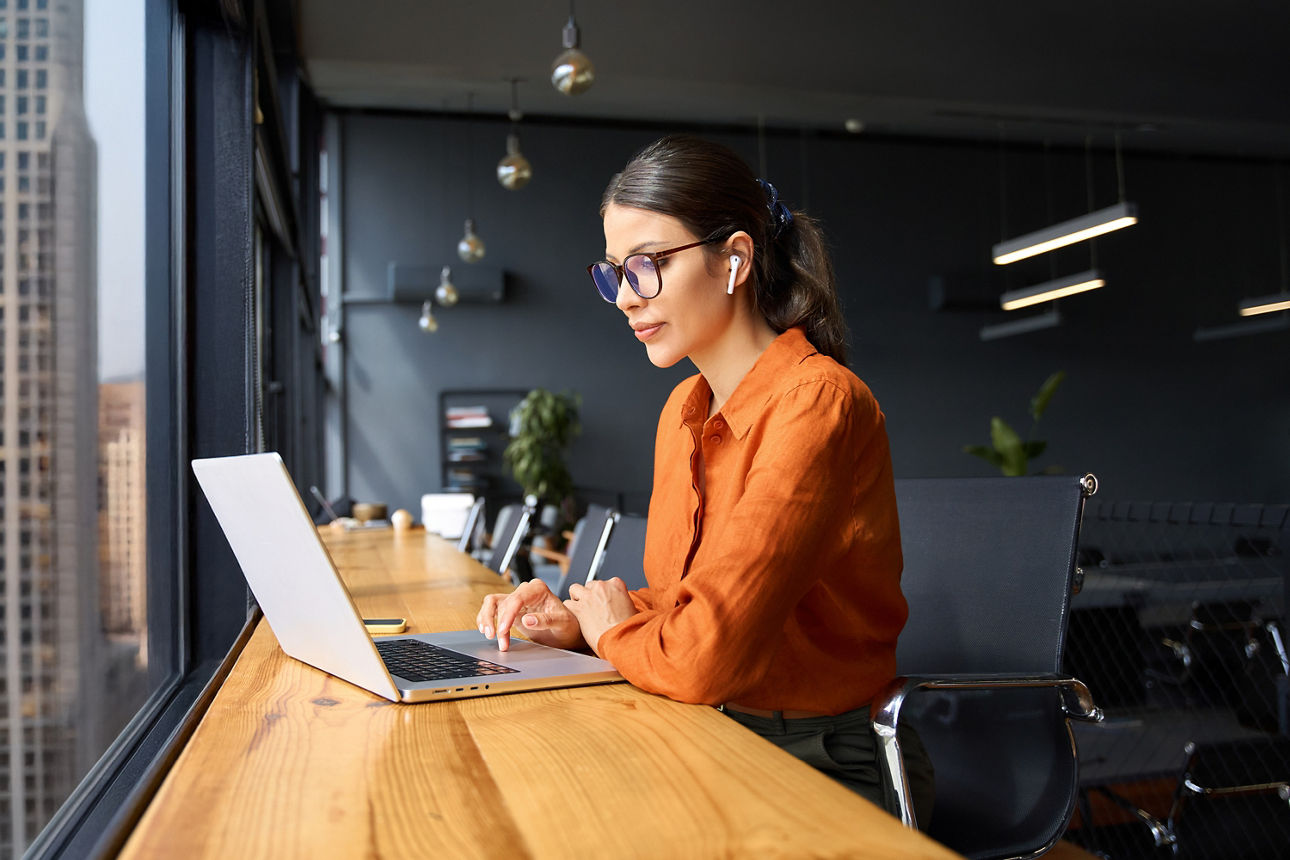 Frau sitzt mit ihrem Laptop am Tisch und arbeitet