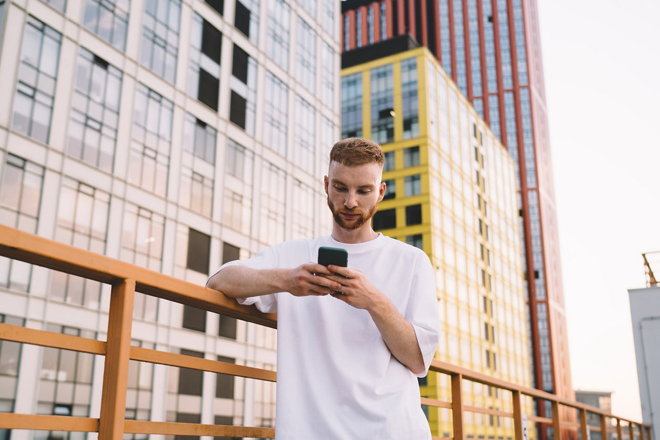 Mann steht mit Smartphone vor Hochhäusern