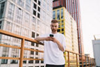 Junger Mann mit Handy vor Häusern