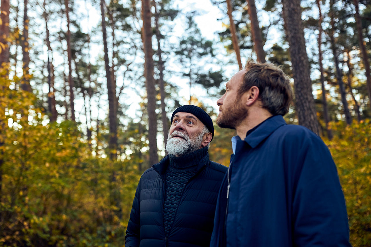 Zwei Männer stehen im Wald und sehen in den Himmel