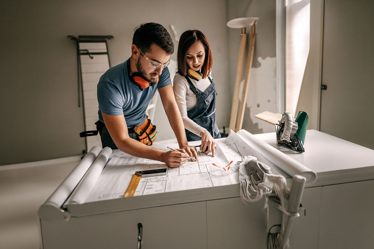 Mann und Frau besprechen einen Bauplan auf einer Baustelle