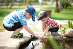 Zwei Kinder spielen mit ihren Händen im Wasser