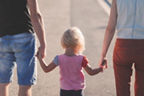 Ein Mann und eine Frau haben ein Kind an der Hand