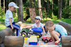 Drei Kinder sitzen im Sandkasten und spielen