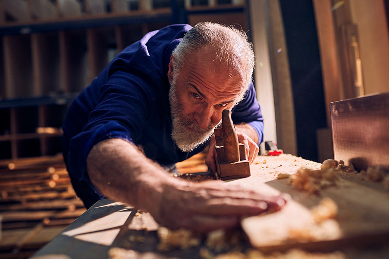 Älterer Handwerker bei der Arbeit in der Holzwerkstatt