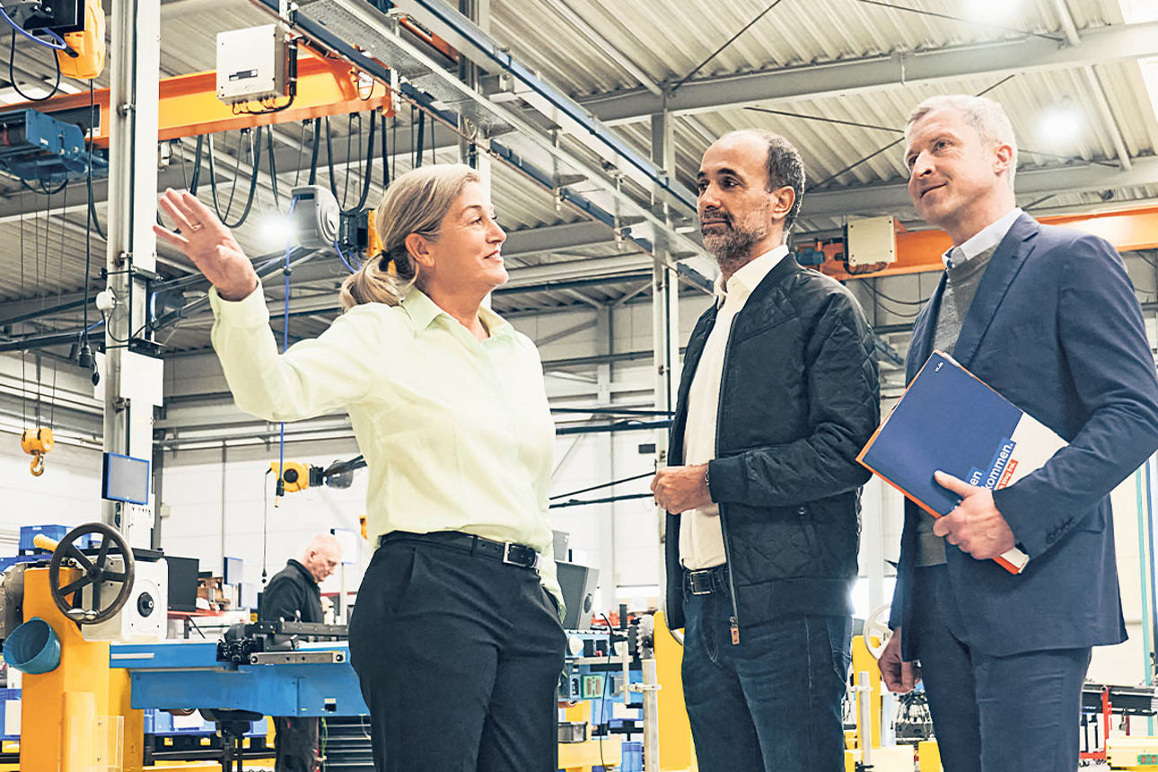 Drei Geschäftsleute stehen in einer Fabrikhalle
