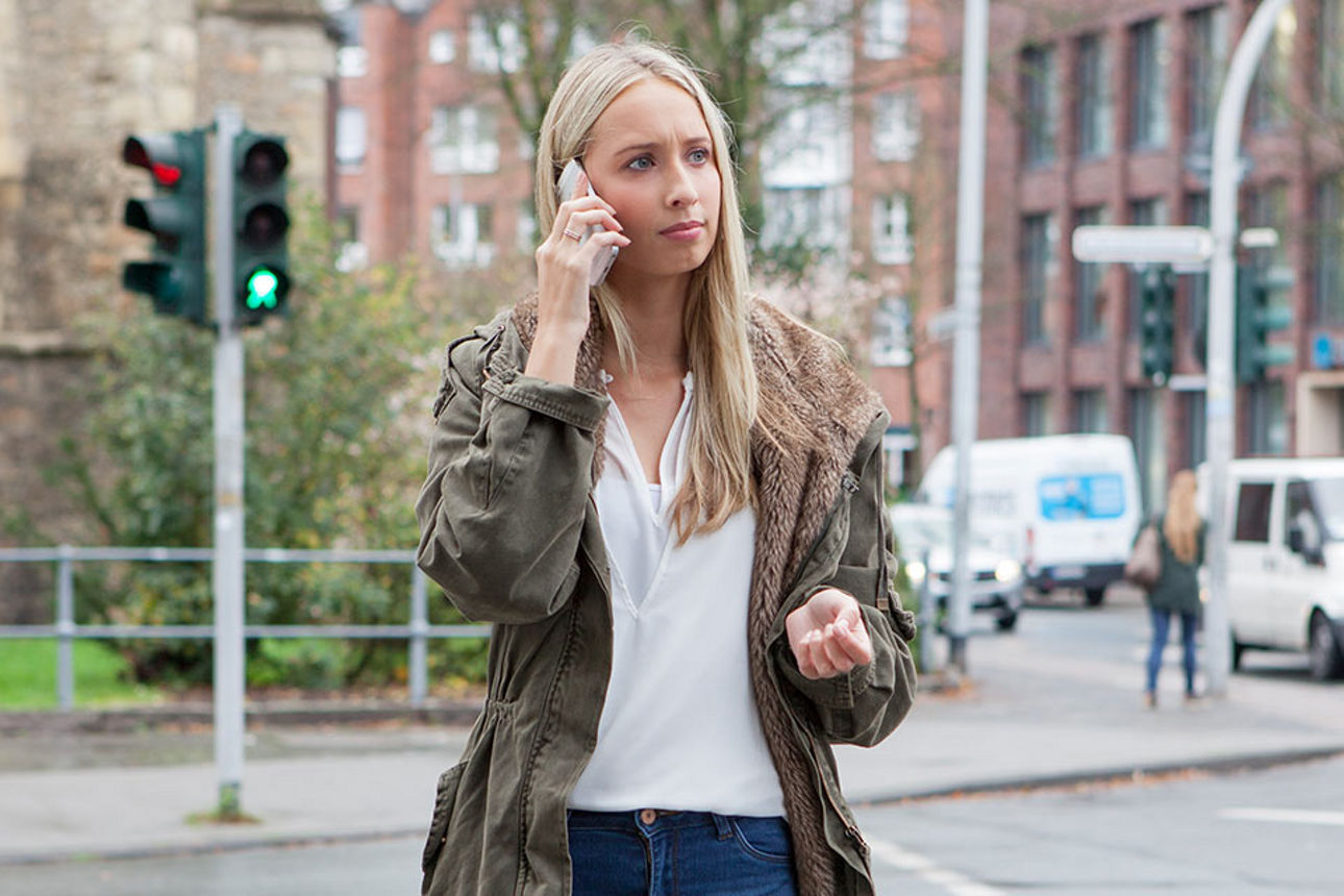 Eine junge Frau tätigt einen Anruf mit ihrem Smartphone