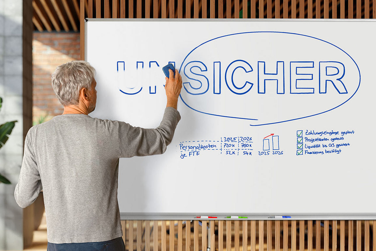 Junger Mann in Latzhose übermalt den Schriftzug "Unmöglich" auf einer Wand