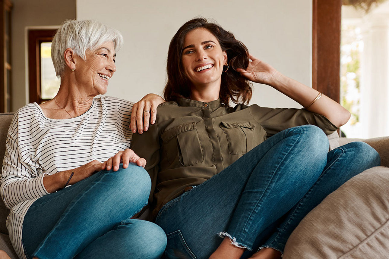 Frauen zweier Generationen sitzen lachend auf einem Sofa