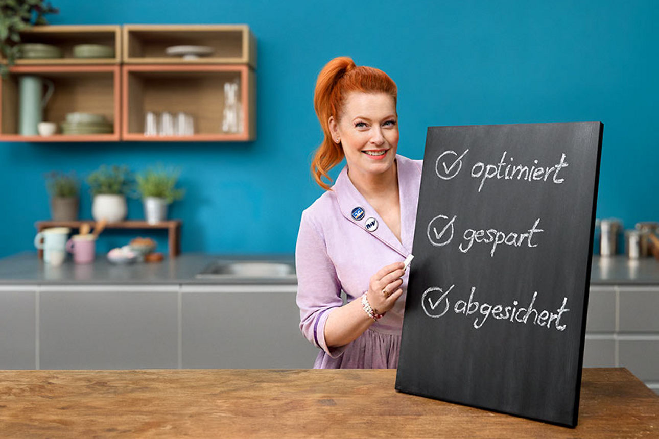 Enie van de Meiklokjes präsentiert die Vorteile des Versicherungs-Checks auf einer Kreidetafel